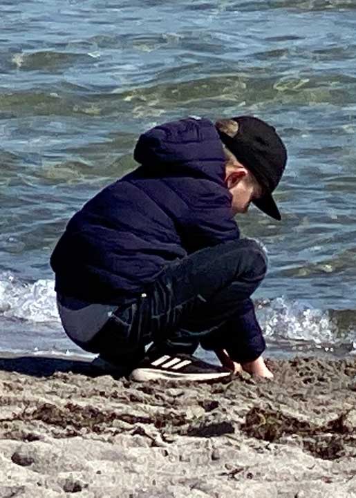 Junge hockt am Strand Junge hockt am Strand